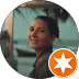 Mujer sonriente en perfil circular con fondo de playa e insignia naranja de estrella blanca.
